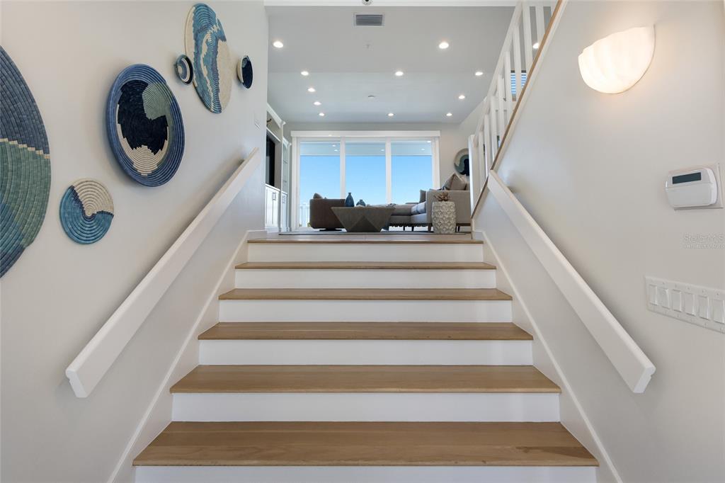 A staircase with wooden treads leads up to a living area with large glass doors — 585 BUTTONWOOD BAY DRIVE, BOCA GRANDE, FL