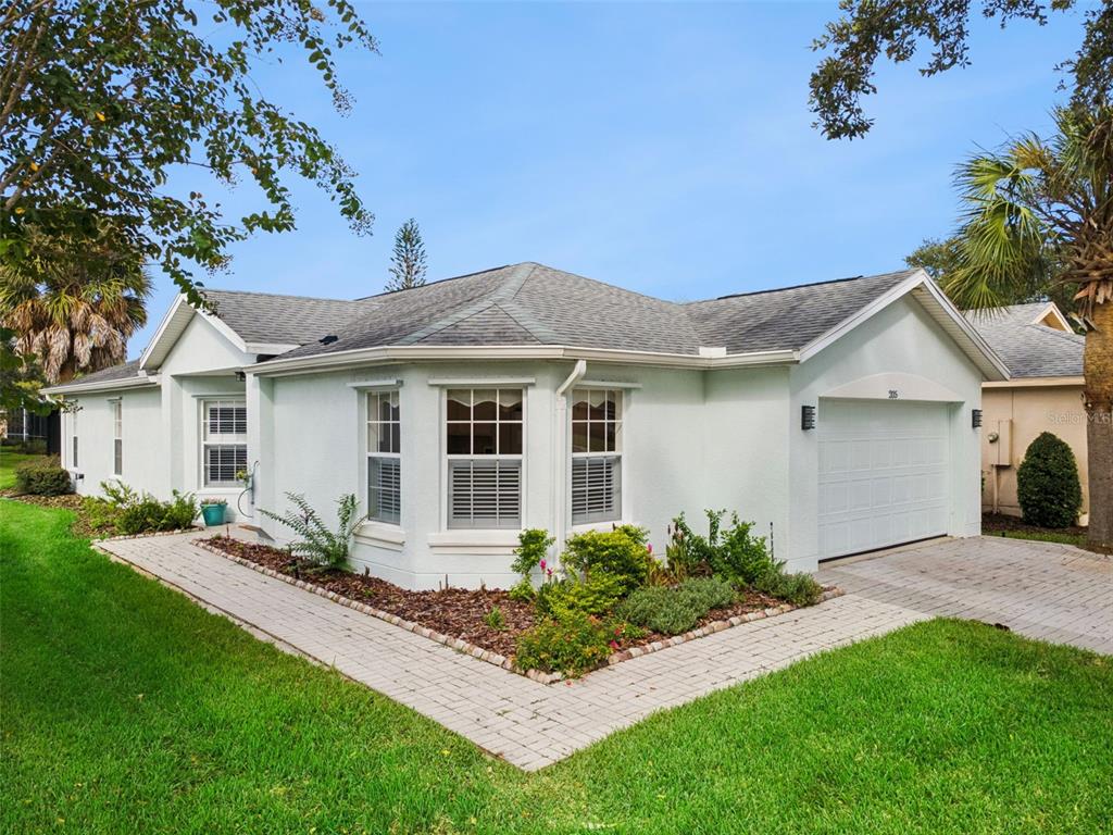 A light-colored single-story house with a paved walkway, a garage, and a landscaped front yard — 205 BELL TOWER CROSSING WEST, KISSIMMEE, FL