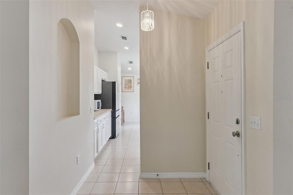 A tiled entryway leads to a kitchen with white cabinets and a black refrigerator — 205 BELL TOWER CROSSING WEST, KISSIMMEE, FL