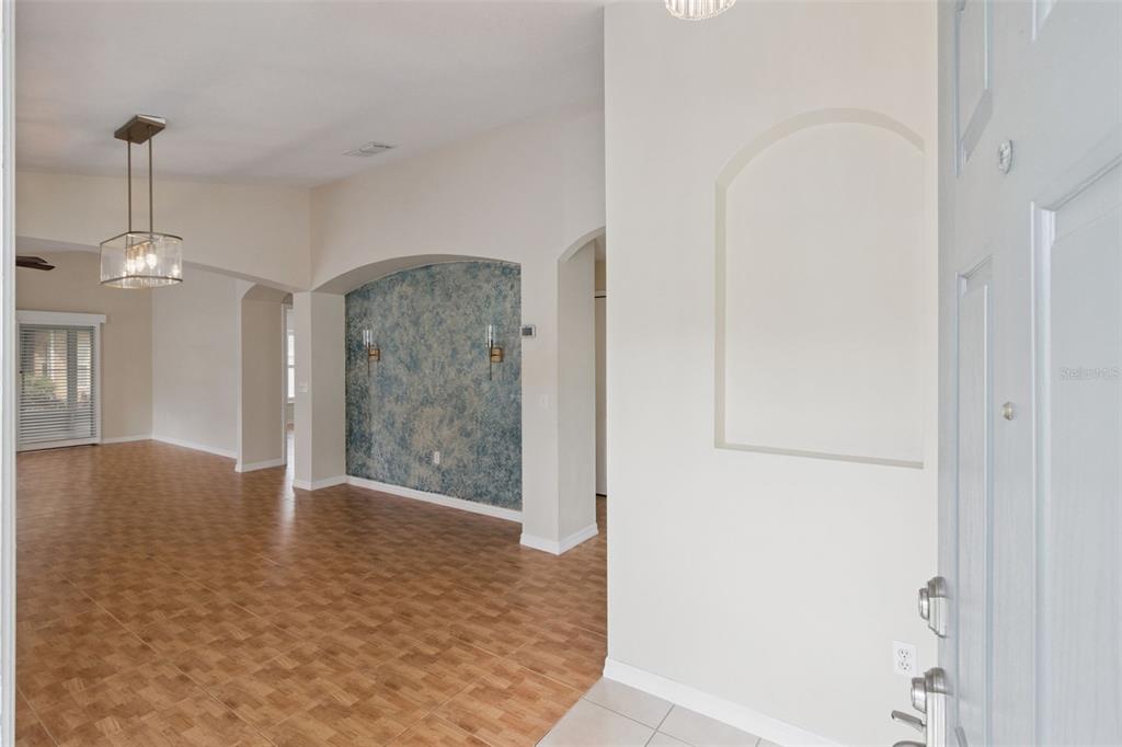 An entryway leads into a living area with tile flooring and a blue accent wall — 205 BELL TOWER CROSSING WEST, KISSIMMEE, FL