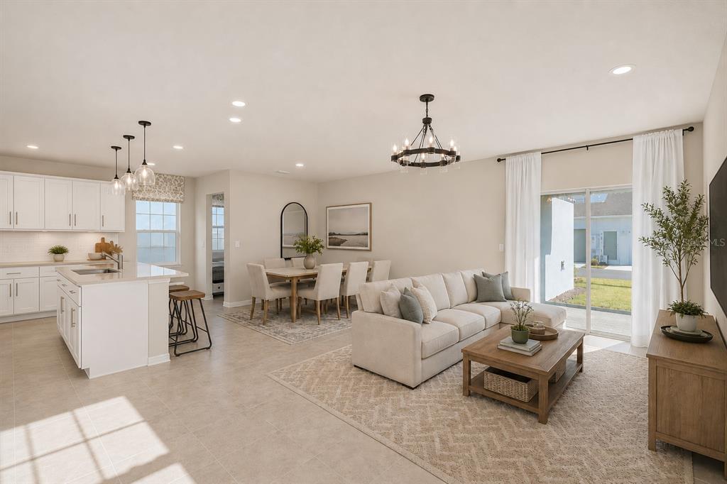 An open-concept living and dining area features a white kitchen, neutral furniture, and sliding doors — 10876 WATERWOOD ALLEY, ORLANDO, FL