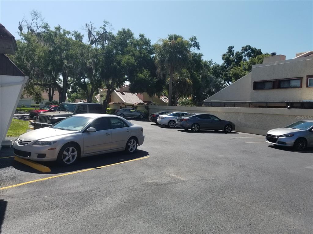 A parking lot with several parked cars sits in front of residential buildings and trees — 2050 HAVENDALE BOULEVARD NW UNIT B, WINTER HAVEN, FL