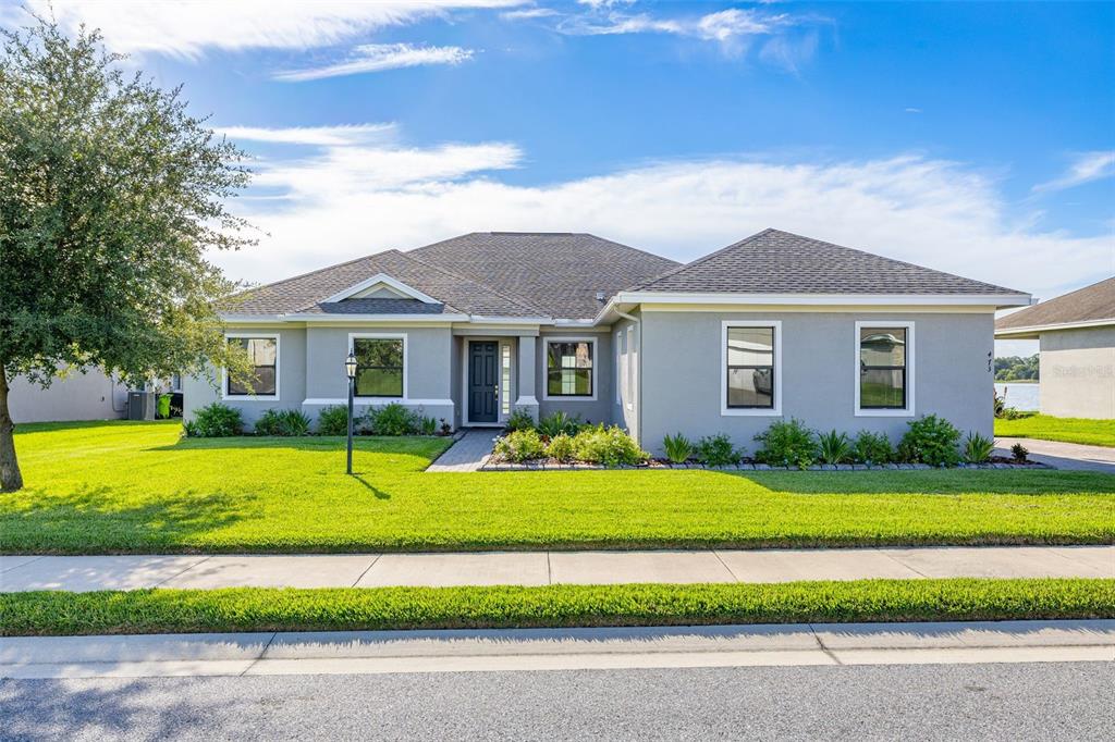 A single-story gray house with a dark shingled roof and a green lawn — 473 LAKE VIEW WAY, AUBURNDALE, FL