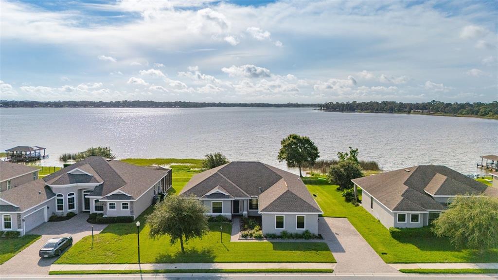 An aerial view shows three suburban houses situated along the shore of a large lake — 473 LAKE VIEW WAY, AUBURNDALE, FL