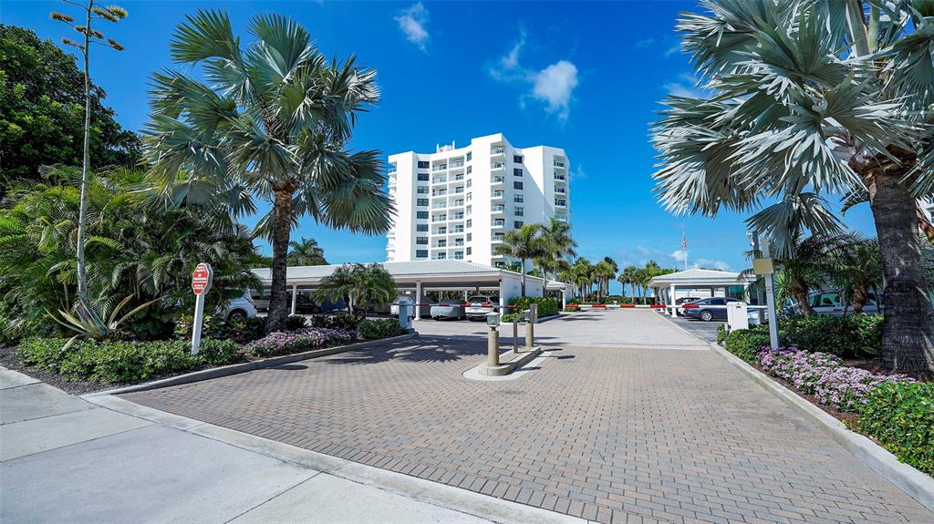 A bright living room features light wood flooring, neutral furniture, and a balcony with palm trees — 1000 LONGBOAT CLUB ROAD UNIT 403, LONGBOAT KEY, FL