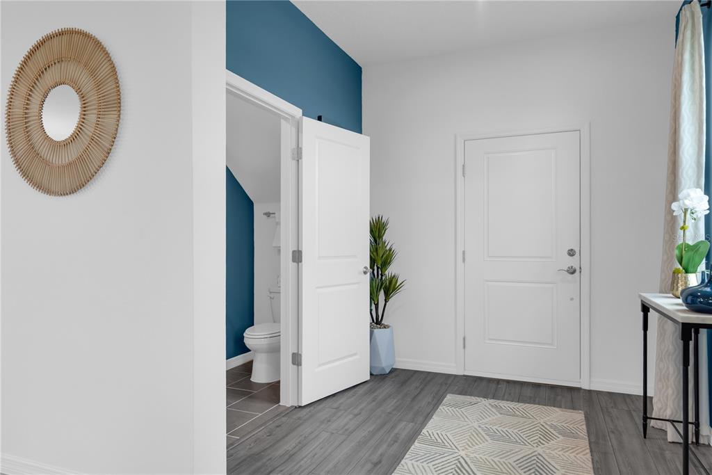 A hallway features gray wood-look flooring, a white door, and an open doorway to a bathroom — 906 CASTLEFORD AVENUE, PALM BAY, FL