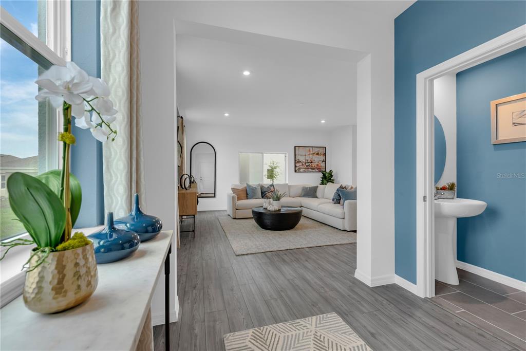 A view from a hallway into a living room with a powder room to the right — 906 CASTLEFORD AVENUE, PALM BAY, FL