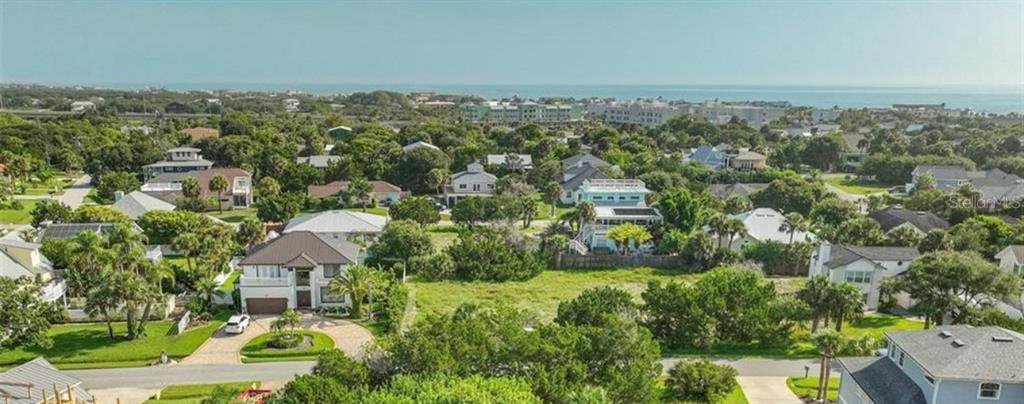 An aerial view shows a coastal neighborhood with houses, lush trees, and the ocean beyond — 204 SEA TURTLE WAY, ST AUGUSTINE, FL