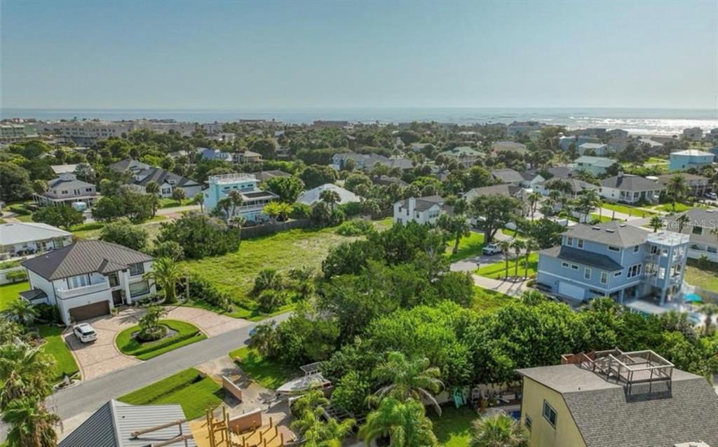 An aerial view shows a vacant grassy lot surrounded by residential houses near the ocean — 204 SEA TURTLE WAY, ST AUGUSTINE, FL