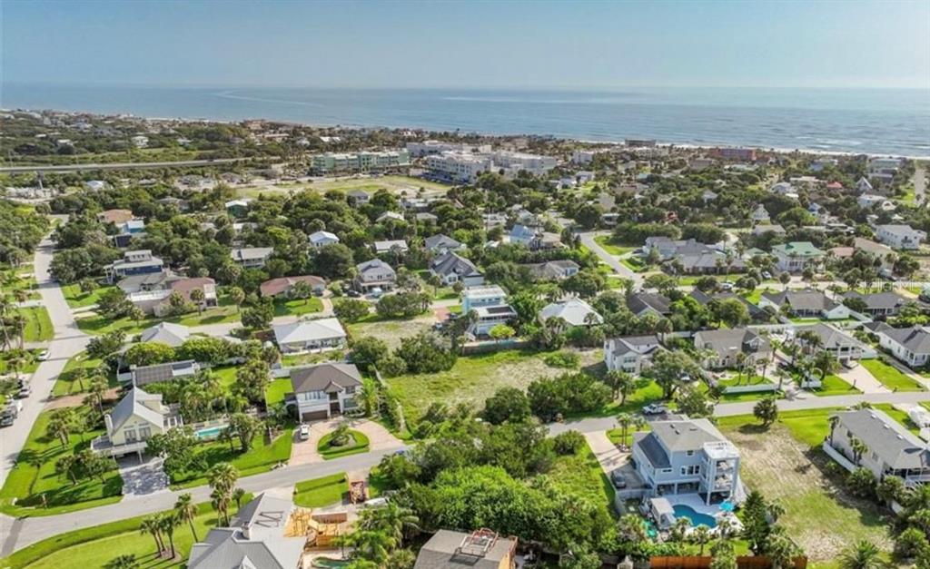 An aerial view shows a coastal neighborhood with houses, green vegetation, and the ocean beyond — 204 SEA TURTLE WAY, ST AUGUSTINE, FL
