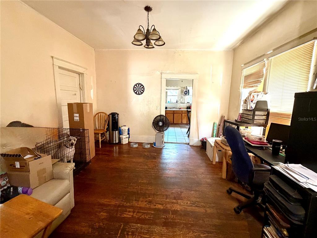 A living room with hardwood floors, a ceiling light fixture, and a dog in a crate — 209 AVENUE C NE, WINTER HAVEN, FL