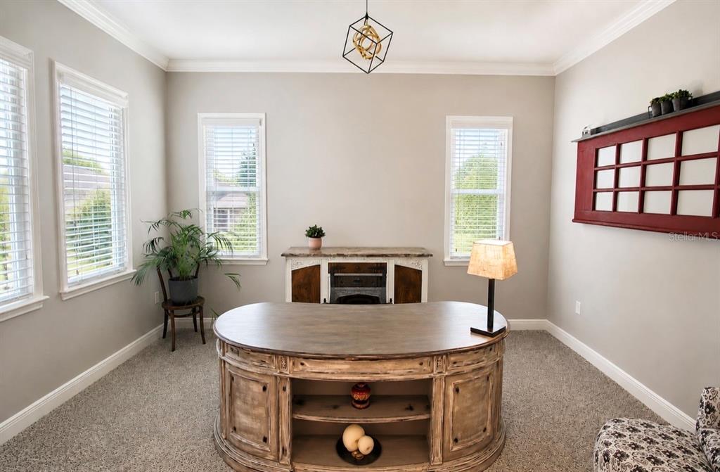 A home office features a large wooden desk, a console table, and a red window frame — 8197 GULLEN DRIVE, MELBOURNE, FL
