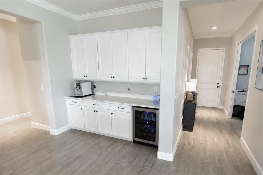 A kitchen wet bar features white cabinets, a marble countertop, and a built-in wine cooler — 8197 GULLEN DRIVE, MELBOURNE, FL