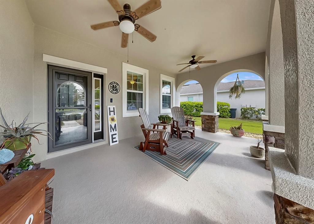 A covered front porch features two wooden chairs, a patterned rug, and two ceiling fans — 2927 130TH AVENUE E, PARRISH, FL