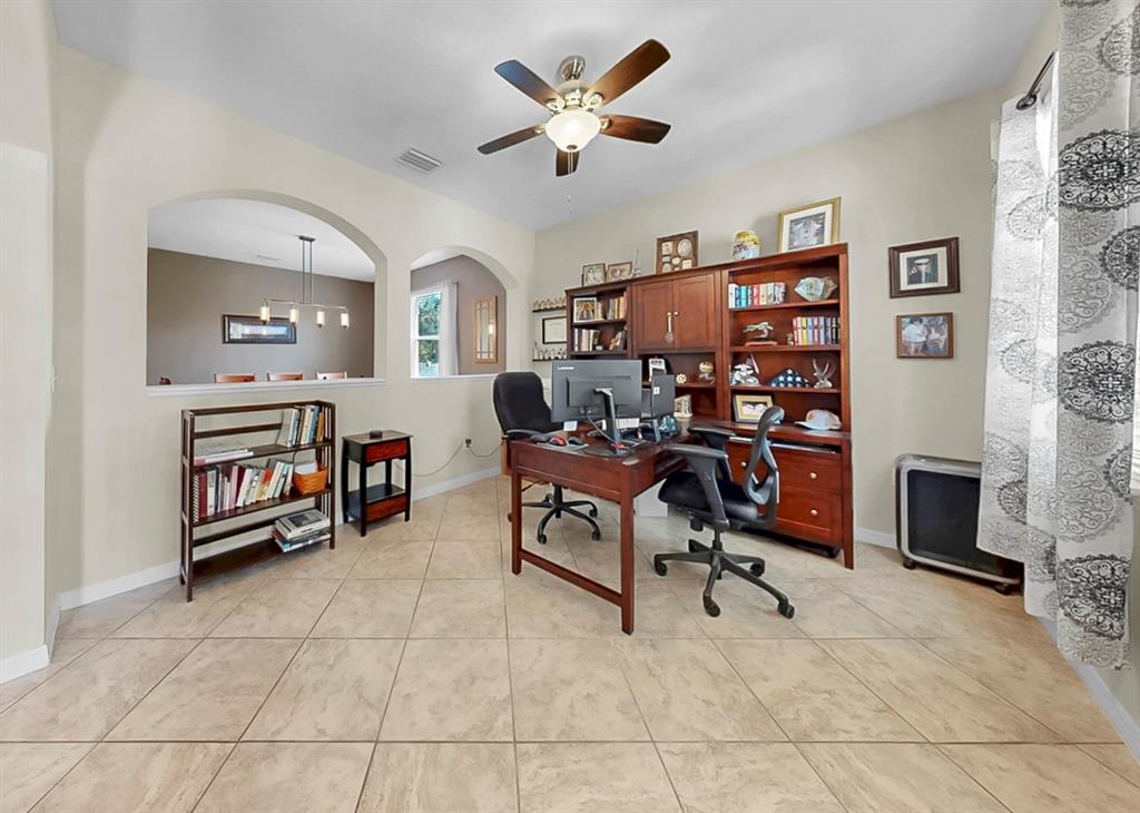 A home office features a wooden desk, a large bookshelf, and tile flooring — 2927 130TH AVENUE E, PARRISH, FL