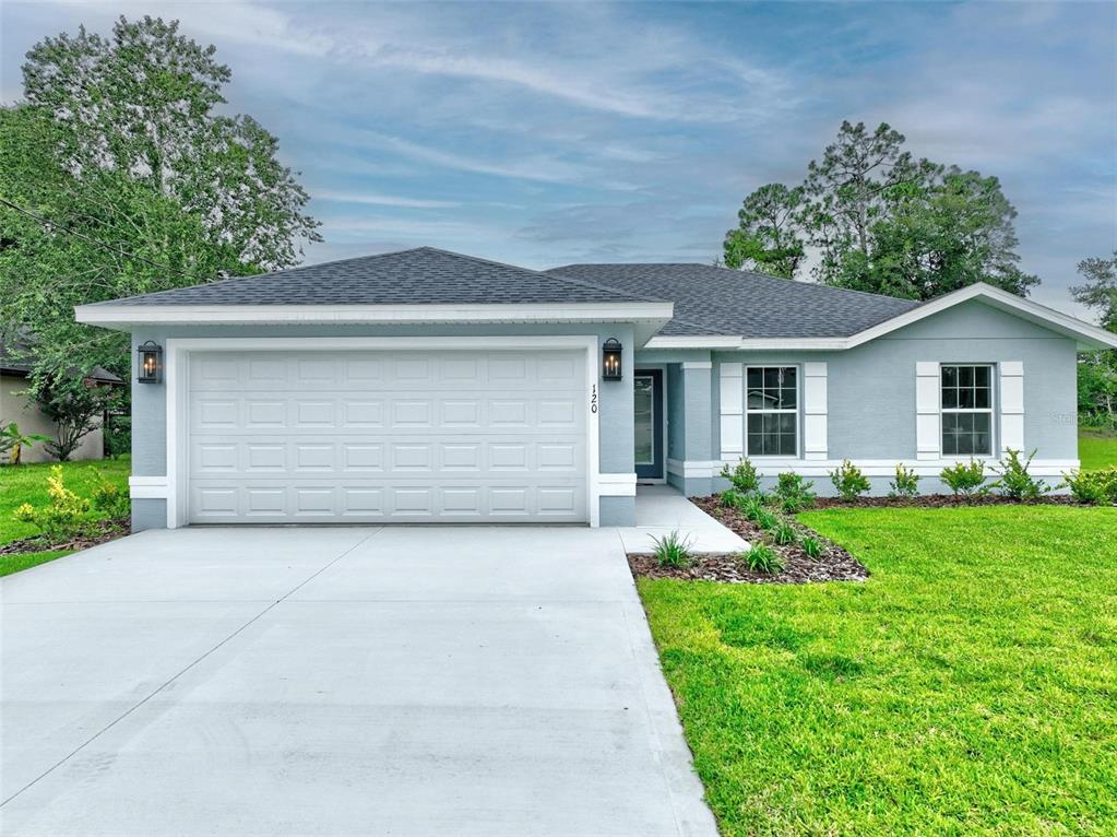 A single-story house with a light blue exterior, a two-car garage, and a concrete driveway — 107 PEPPERDINE DRIVE, PALM COAST, FL