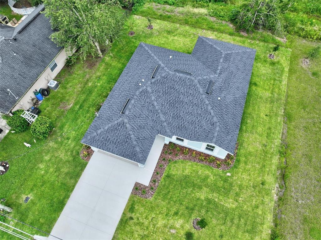 An aerial view shows a house with a gray shingled roof and an attached driveway — 107 PEPPERDINE DRIVE, PALM COAST, FL