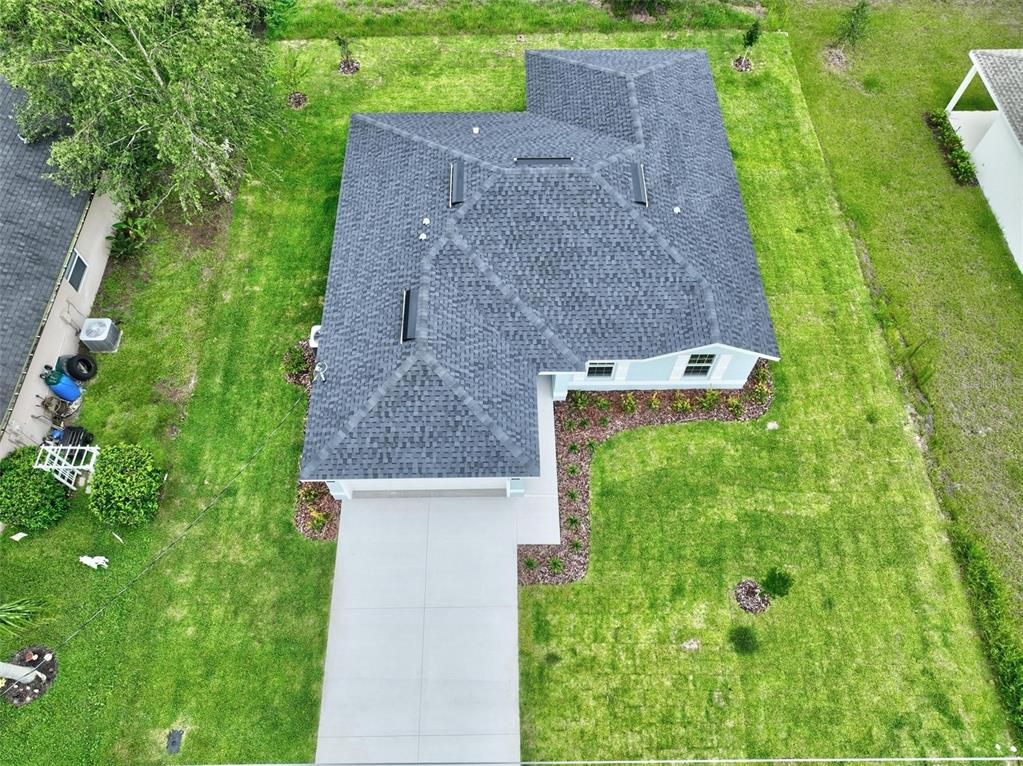 An aerial view of a single-story house with a gray shingled roof and concrete driveway — 107 PEPPERDINE DRIVE, PALM COAST, FL