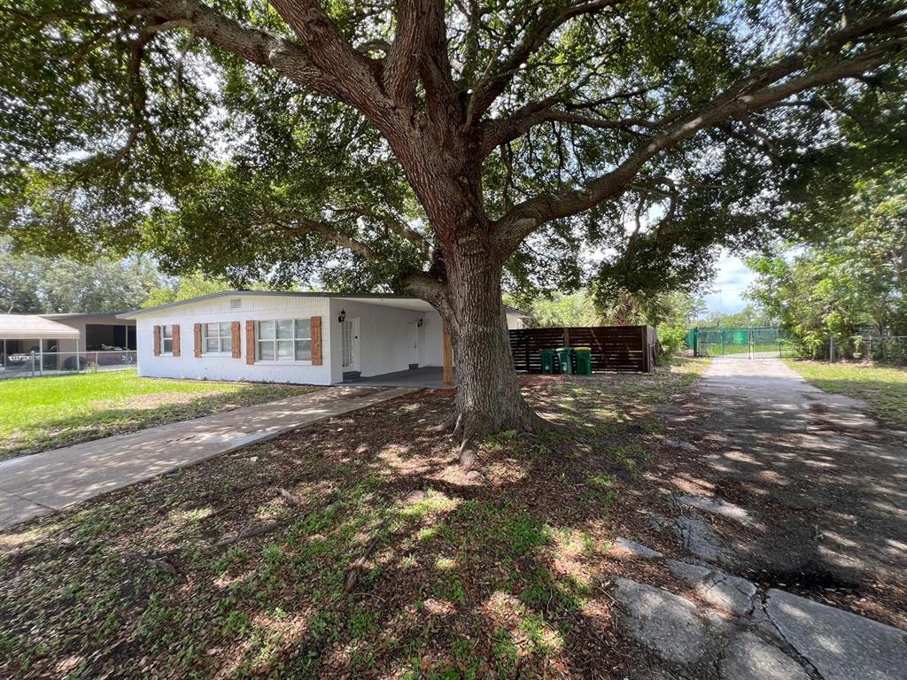 A white single-story house with a large oak tree in the front yard — 1221 CYPRESS LANE, COCOA, FL