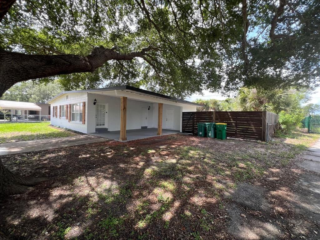 A white house with a covered porch, wooden support posts, and a wooden privacy fence — 1221 CYPRESS LANE, COCOA, FL