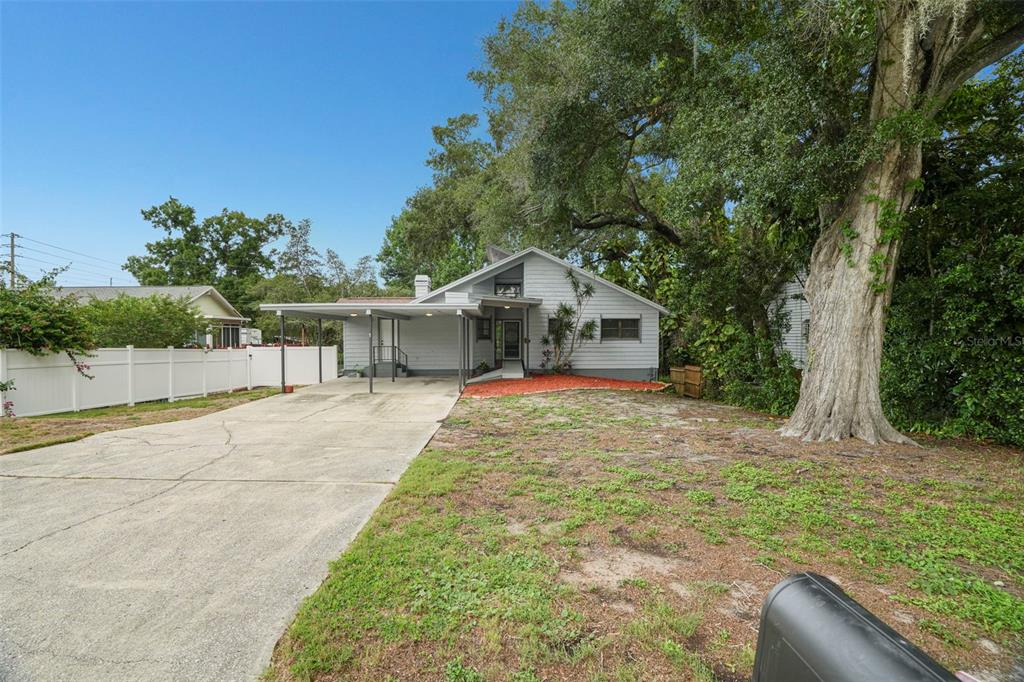 A single-story house with a carport, white vinyl fence, and a large tree in front — 210 EDGEWOOD AVENUE, CLEARWATER, FL
