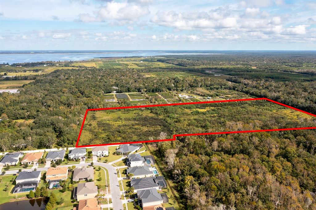 An aerial view shows a large, rectangular vacant lot outlined in red adjacent to a neighborhood — SMARTS PLACE, OVIEDO, FL