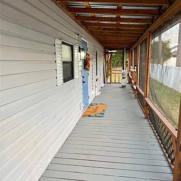 A long, covered wooden porch runs alongside a house with white horizontal siding — 4820 CAPRON STREET, NEW PORT RICHEY, FL