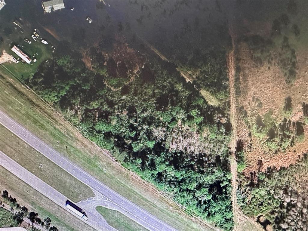 This aerial view shows a wooded lot adjacent to a highway and a parking area — HINES DRIVE, OKEECHOBEE, FL