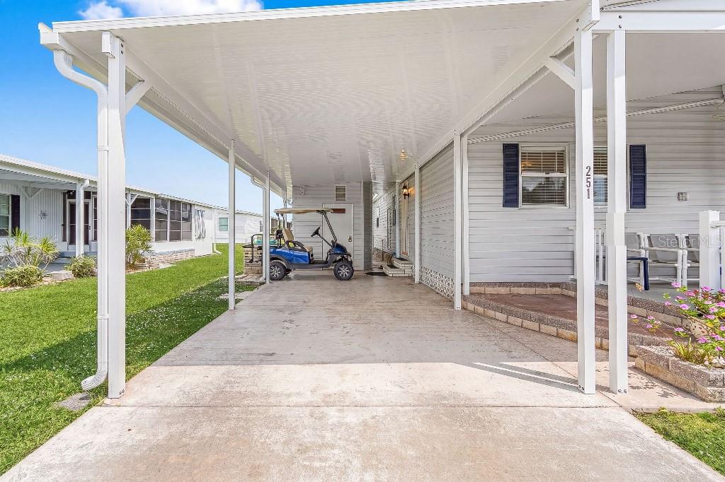 A concrete carport with a white metal roof sits beside a light-colored mobile home — 251 IBIS, PUNTA GORDA, FL