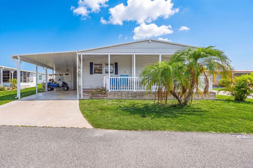 A single-story manufactured home with a carport, a front porch, and a palm tree — 251 IBIS, PUNTA GORDA, FL