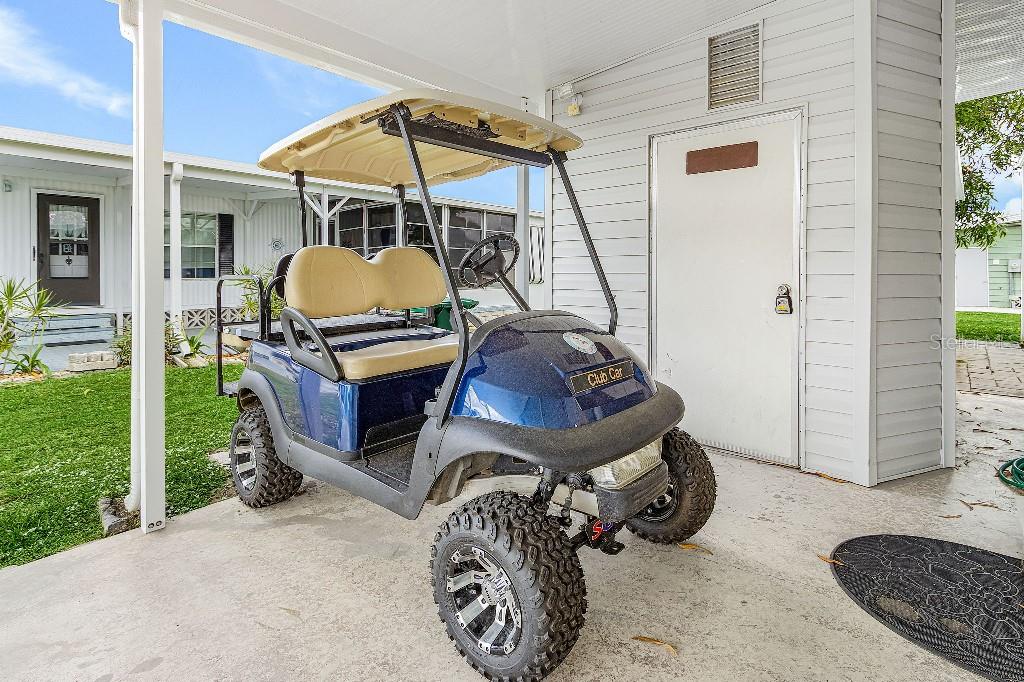 A blue golf cart is parked on a concrete patio under a covered carport — 251 IBIS, PUNTA GORDA, FL