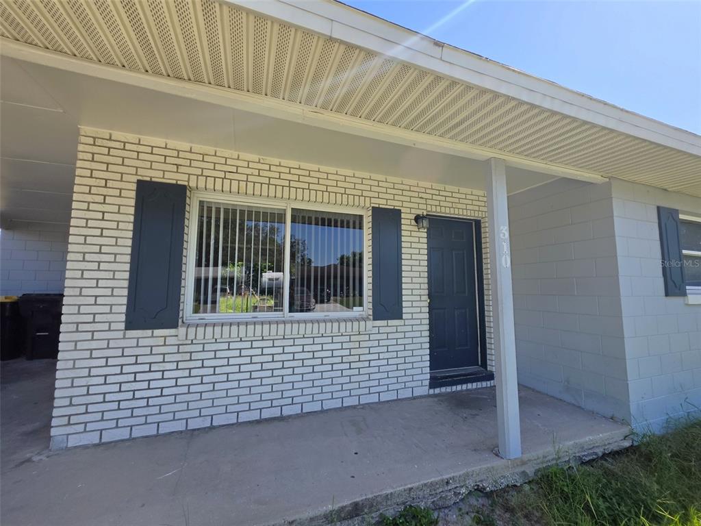 A white brick house exterior features a front porch, a dark door, and blue shutters — 310 VANIMAN AVENUE, WINTER HAVEN, FL