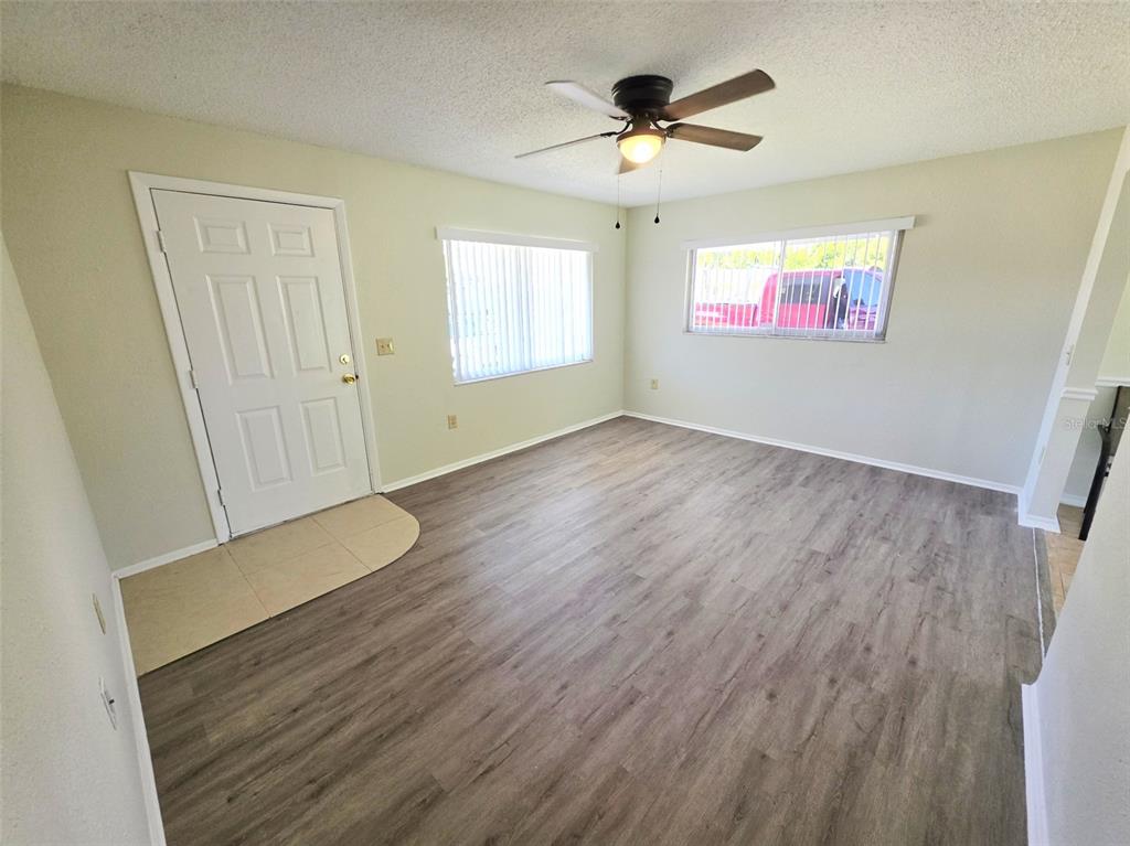 An empty room features light-colored walls, wood-look flooring, a ceiling fan, and two windows — 310 VANIMAN AVENUE, WINTER HAVEN, FL