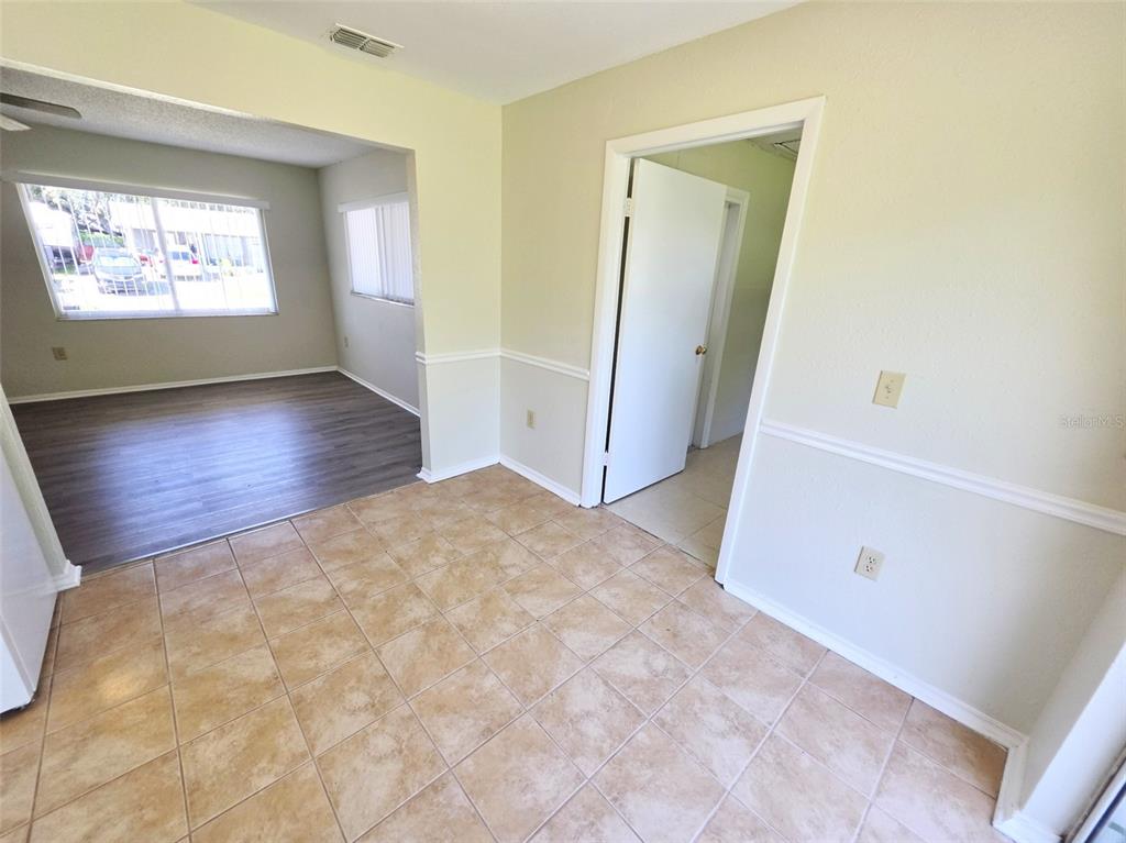 A room with tan tile flooring transitions into an adjacent living area with wood-look flooring — 310 VANIMAN AVENUE, WINTER HAVEN, FL