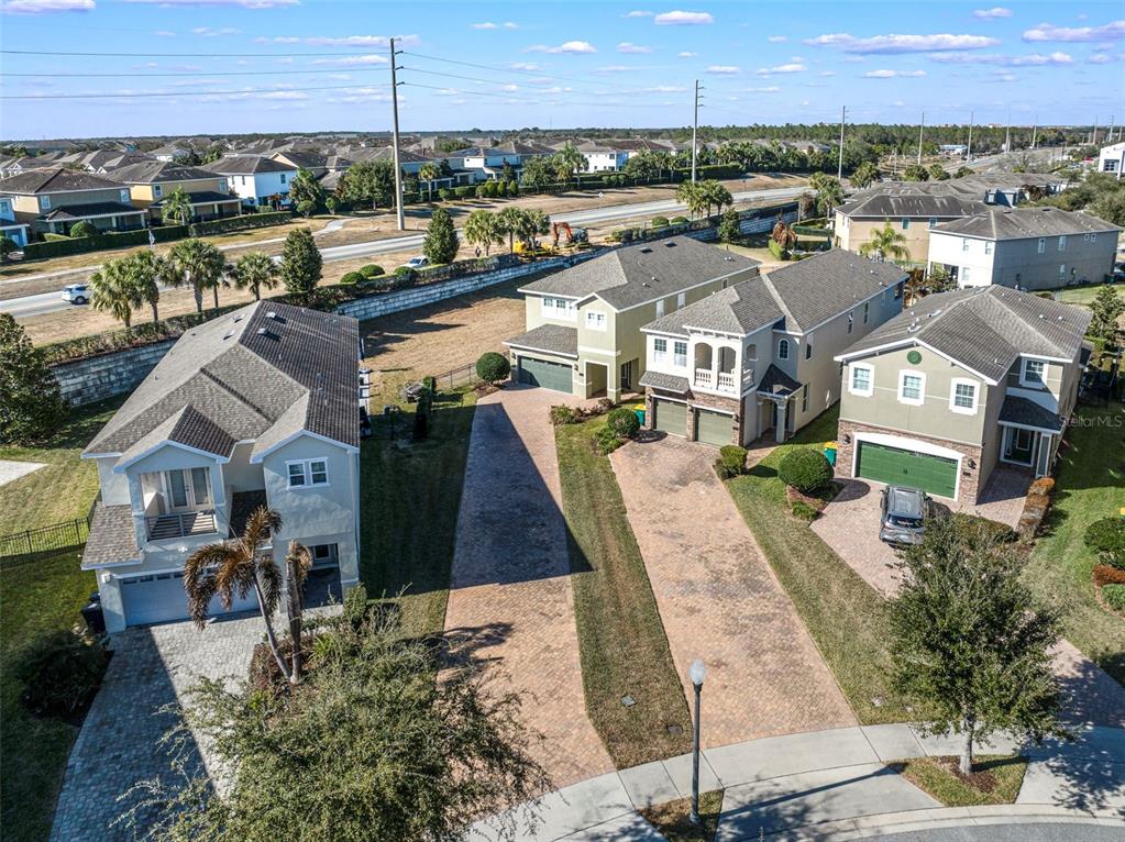 An aerial view shows three suburban houses with paved driveways and green lawns — 180 MINTON LOOP, KISSIMMEE, FL