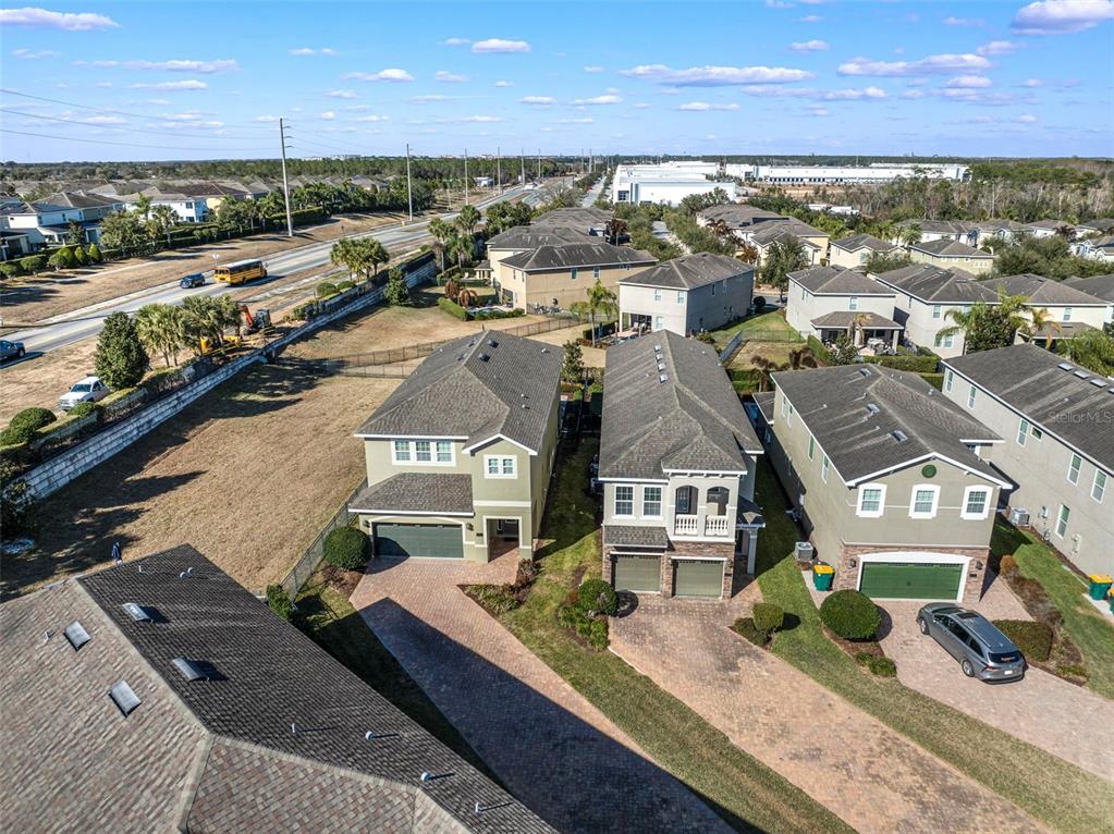 An aerial view shows three suburban houses with paved driveways and adjacent grassy lots — 180 MINTON LOOP, KISSIMMEE, FL