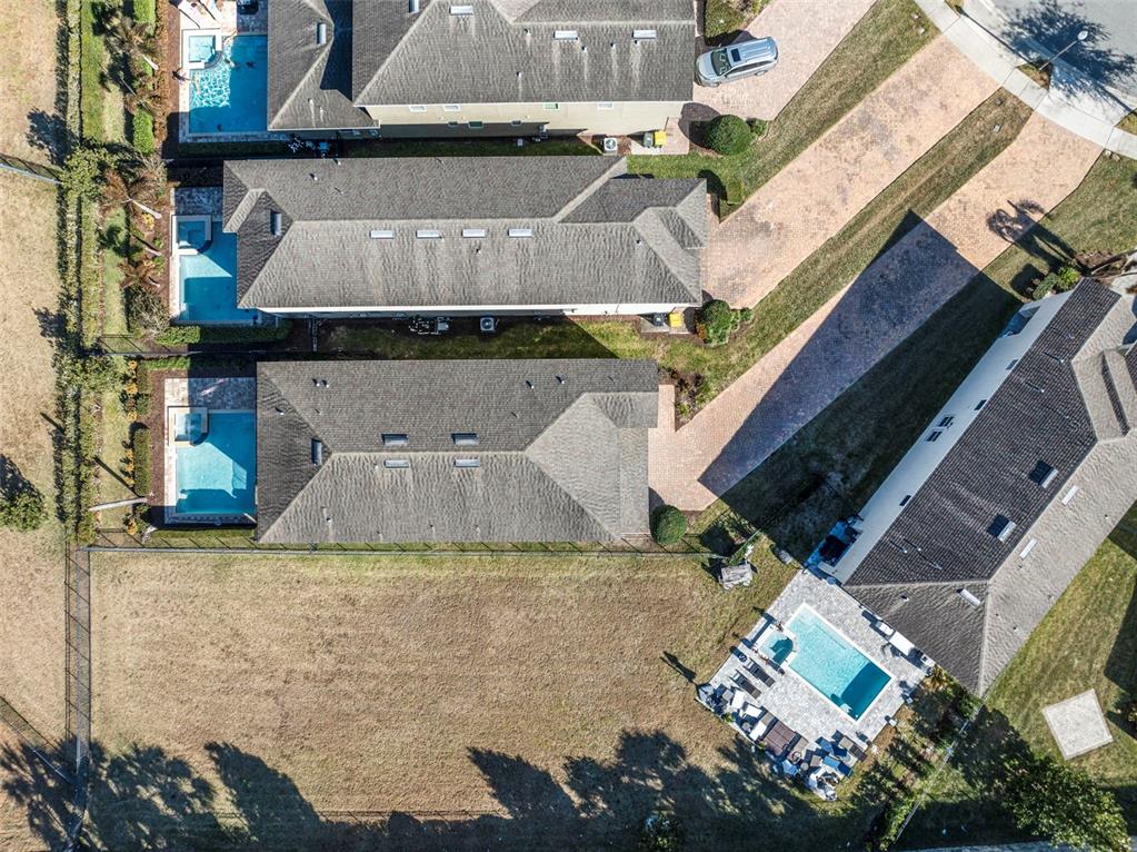 An aerial view shows several suburban houses with swimming pools and a large vacant lot — 180 MINTON LOOP, KISSIMMEE, FL