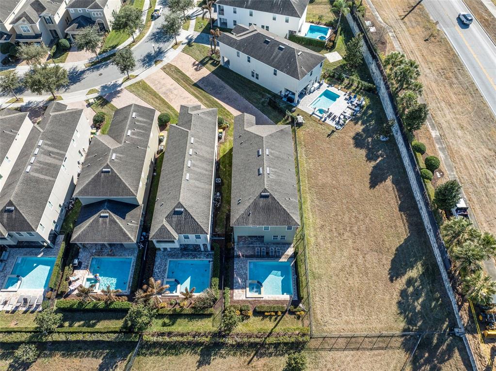 An aerial view shows several residential houses with private swimming pools and a large vacant lot — 180 MINTON LOOP, KISSIMMEE, FL