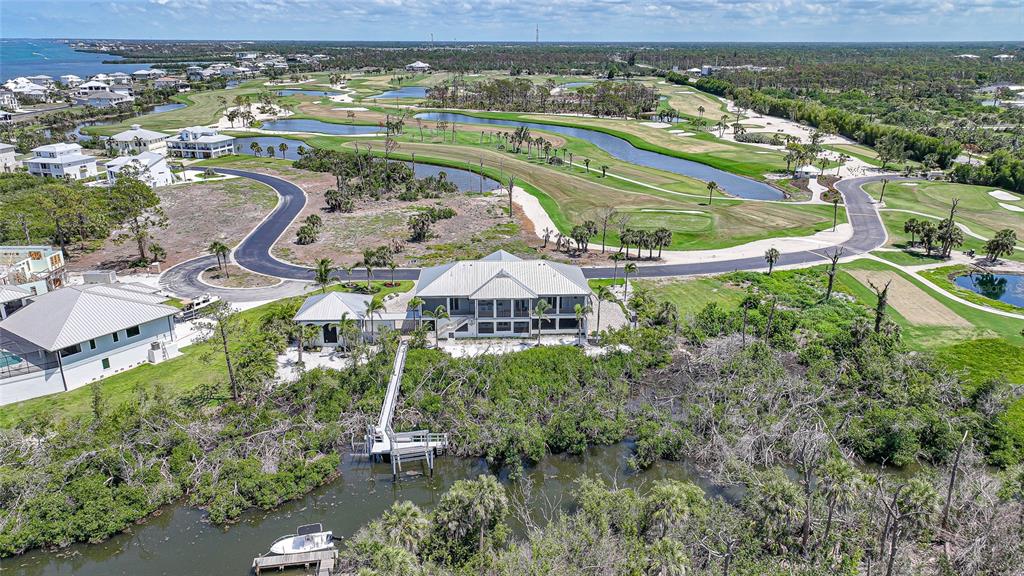 An aerial view shows a waterfront house with a private dock and a golf course — 10161 EAGLE PRESERVE DRIVE, ENGLEWOOD, FL