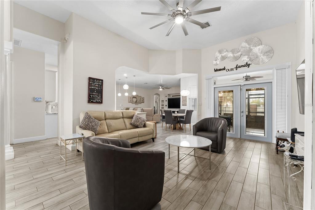 A living room features light wood-look tile flooring, a tan sofa, and two dark armchairs — 2770 SWOOP CIRCLE, KISSIMMEE, FL