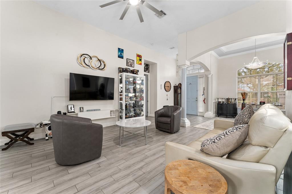 A living room with gray wood-look tile flooring, a white sofa, and two gray armchairs — 2770 SWOOP CIRCLE, KISSIMMEE, FL