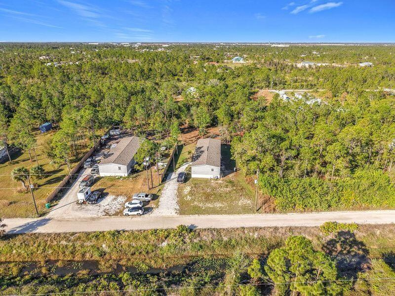 An aerial view shows two manufactured homes on a gravel lot surrounded by dense forest — 8325 STRASSE BOULEVARD, PUNTA GORDA, FL