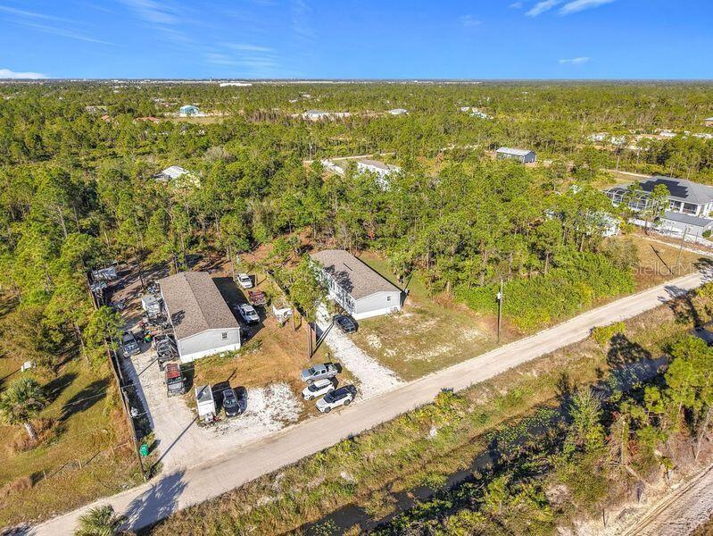 An aerial view shows two manufactured homes on a large, wooded lot with gravel driveways — 8325 STRASSE BOULEVARD, PUNTA GORDA, FL