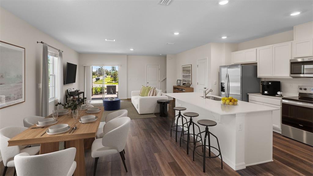 An open-concept living area features a dining table, kitchen island with stools, and a sofa — 16534 BARBOURS CREEK WAY, WINTER GARDEN, FL