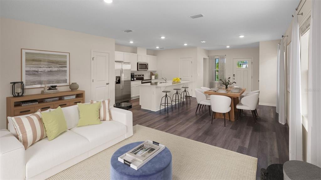 An open-concept living room and kitchen featuring white cabinetry, a kitchen island, and wood flooring — 16534 BARBOURS CREEK WAY, WINTER GARDEN, FL