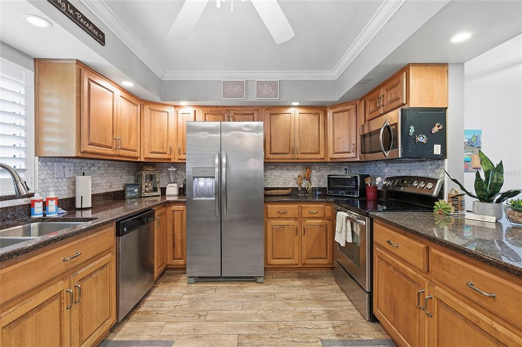 A kitchen with wood cabinets, stainless steel appliances, and dark granite countertops — 111 N ATLANTIC AVENUE UNIT A101, NEW SMYRNA BEACH, FL