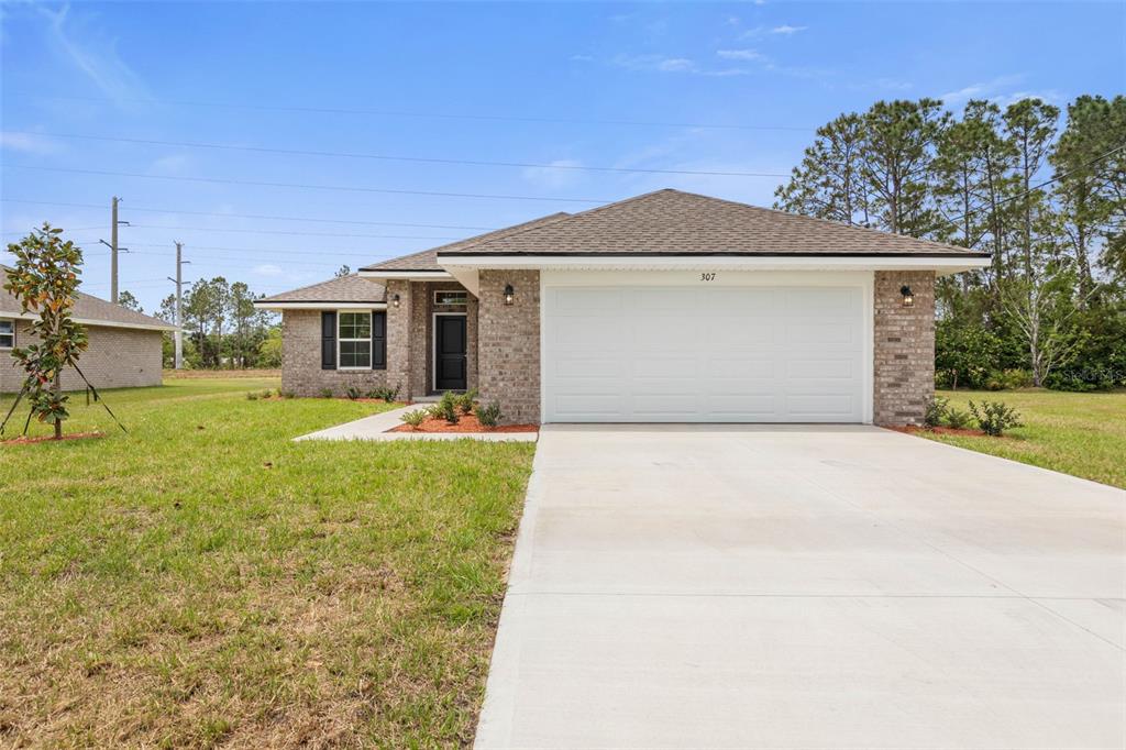 A single-story brick house with a two-car garage and a concrete driveway — 47 BRUNSWICK LANE, PALM COAST, FL