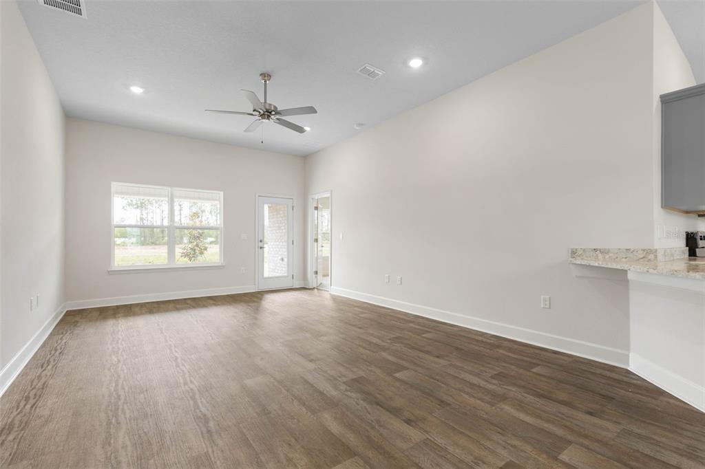 A kitchen features white cabinets, stainless steel appliances, and a quartz island with a sink — 47 BRUNSWICK LANE, PALM COAST, FL