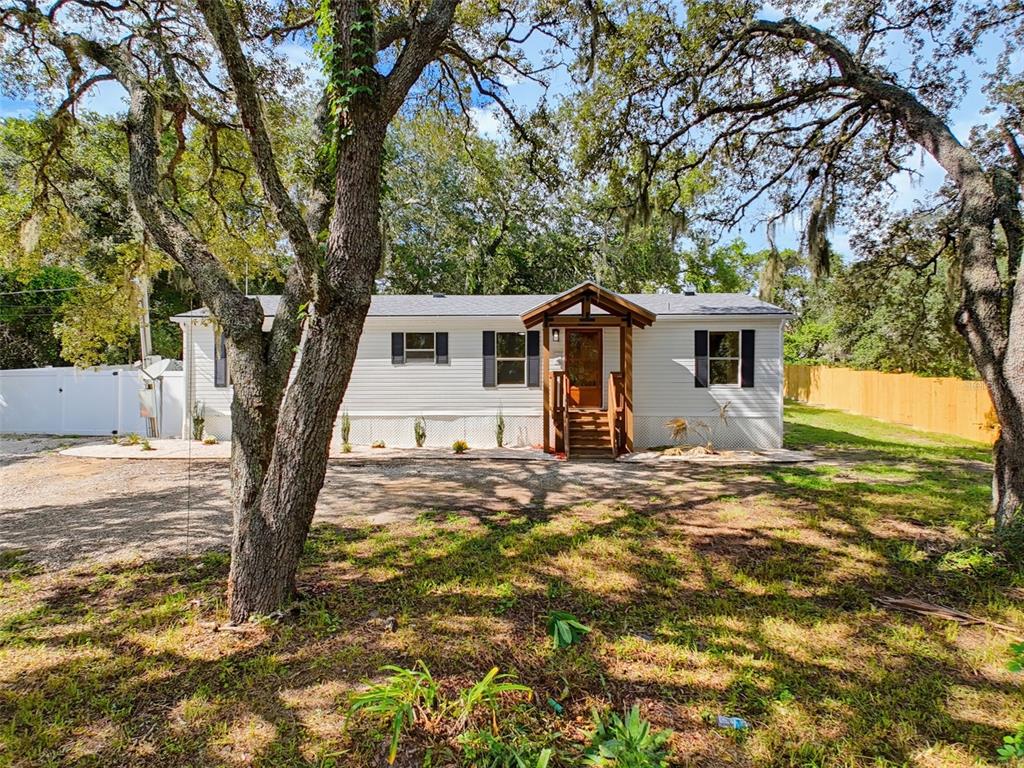 A single-story manufactured home with white siding, black shutters, and a wooden front porch — 9637 PASSAIC DRIVE, HUDSON, FL