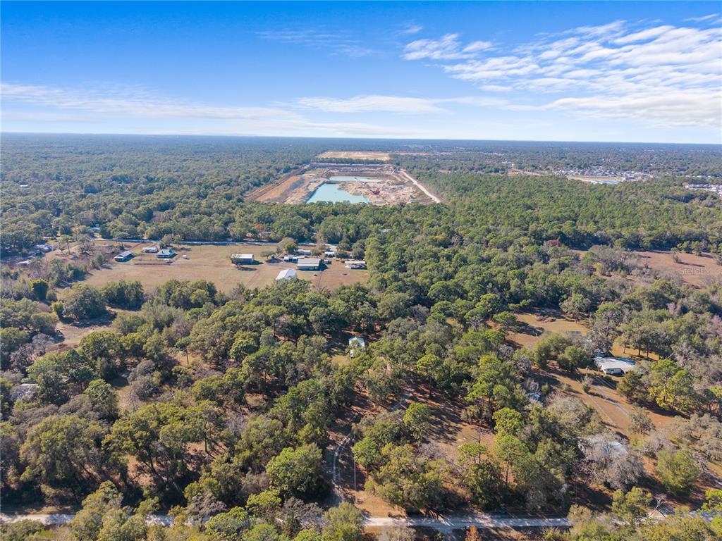 An aerial view shows a rural property with a house, outbuildings, and surrounding wooded land — 0 DEASON DRIVE, SPRING HILL, FL